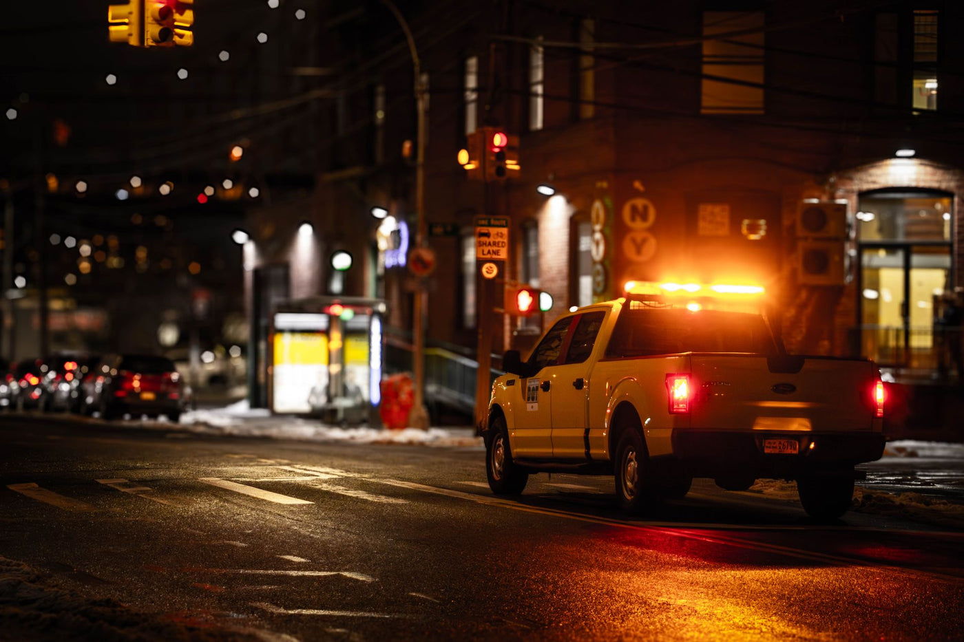 Utility truck with flashing lights on a dimly lit New York street at night.