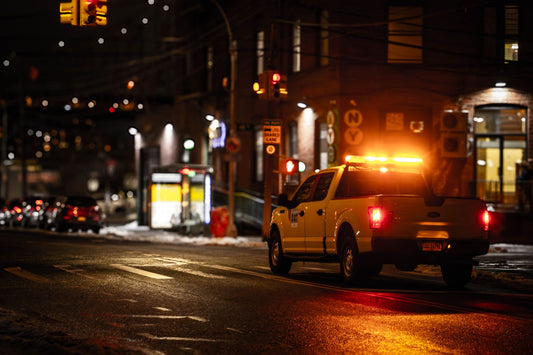 Utility truck with flashing lights on a dimly lit New York street at night.