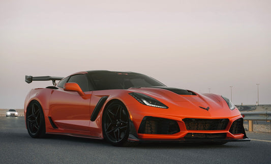 Vibrant orange sports car with aerodynamic design parked on an asphalt road at dusk, showcasing luxury and speed.